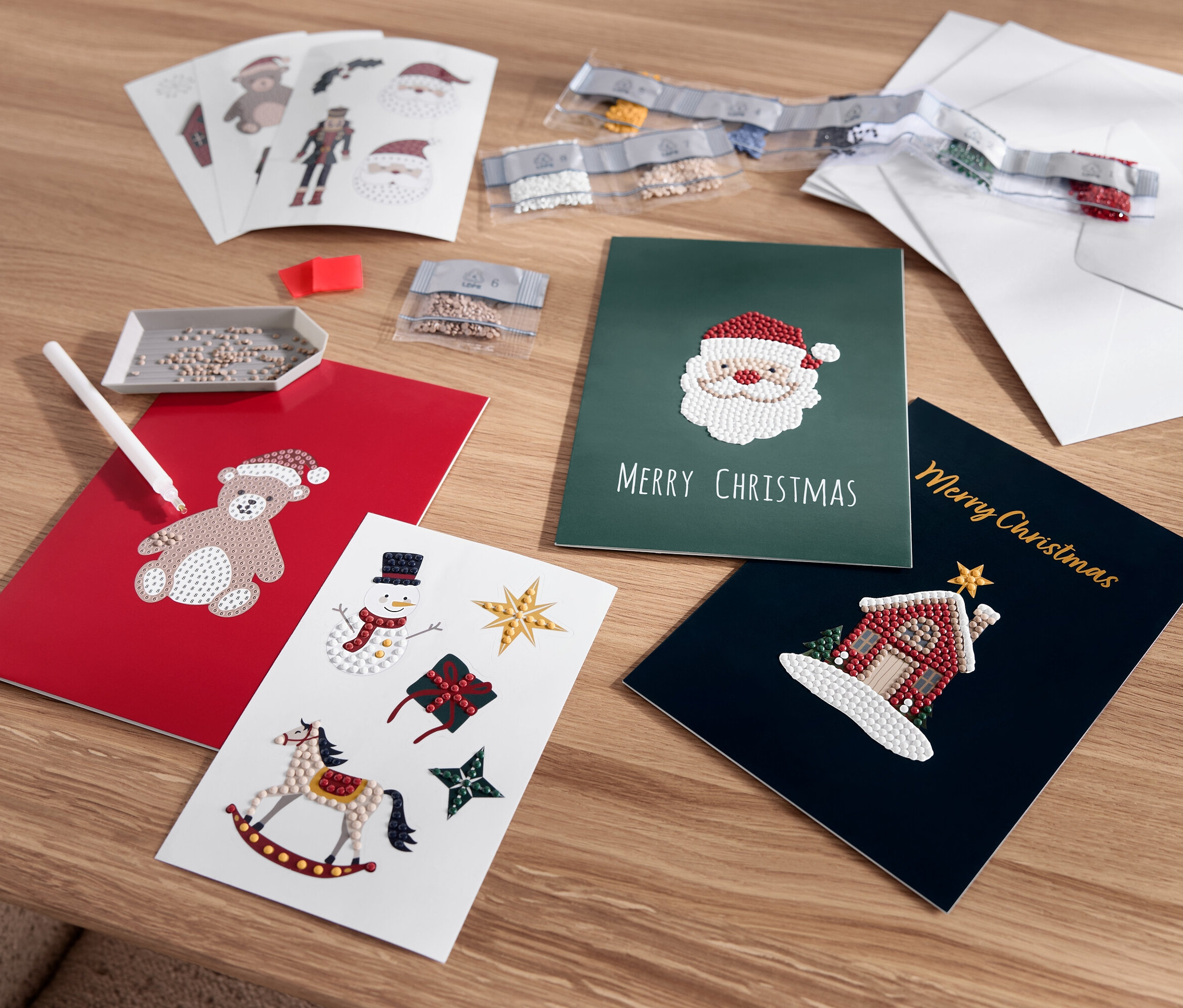 Rozłożone kartki świąteczne z motywami misia, Świętego Mikołaja, bałwana i domu.