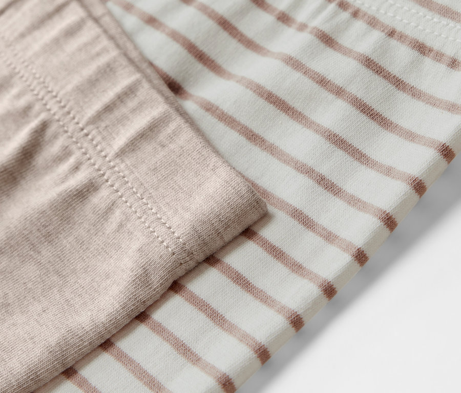 Zbliżenie na legginsy dziecięce, 5 par, jedne beżowe, drugie w brązowe paski.