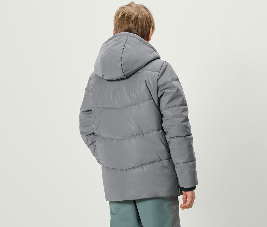 Chłopiec tyłem do kamery ma na sobie szarą kurtkę puchową Reflektierende Kinder-Steppjacke i spodnie.