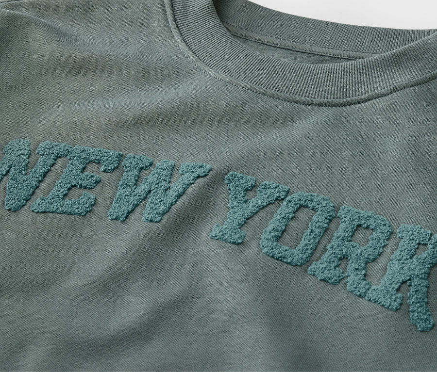 Zbliżenie na bluzę dziecięcą z napisem NEW YORK z tkaniny frotte.