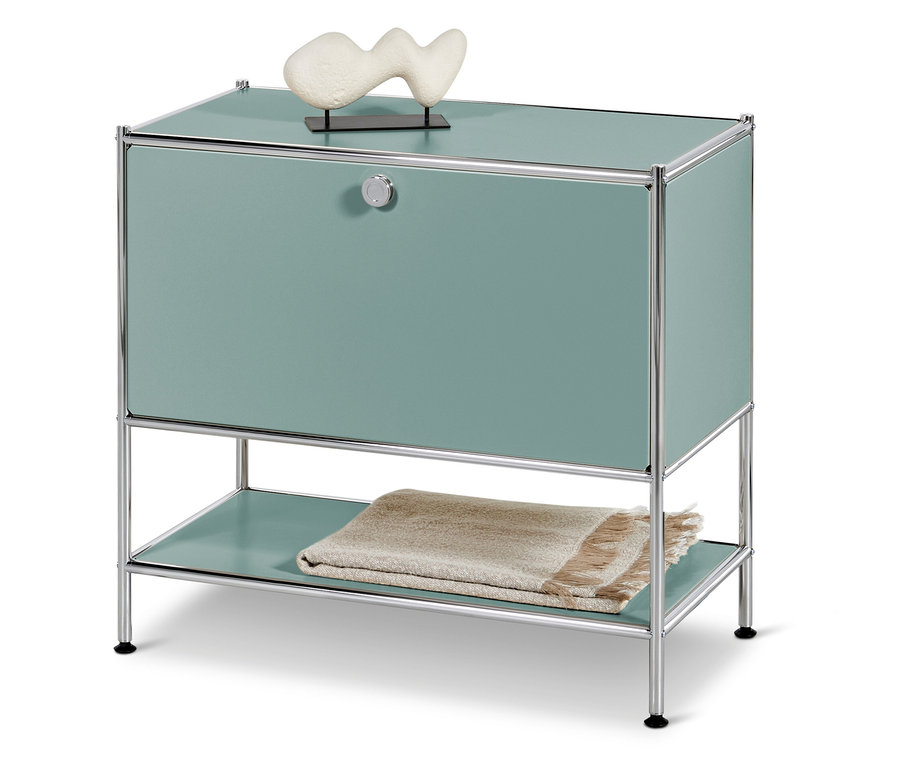 Turkusowa szafka z chromowaną ramą, na górze biała dekoracja, koc na dole.