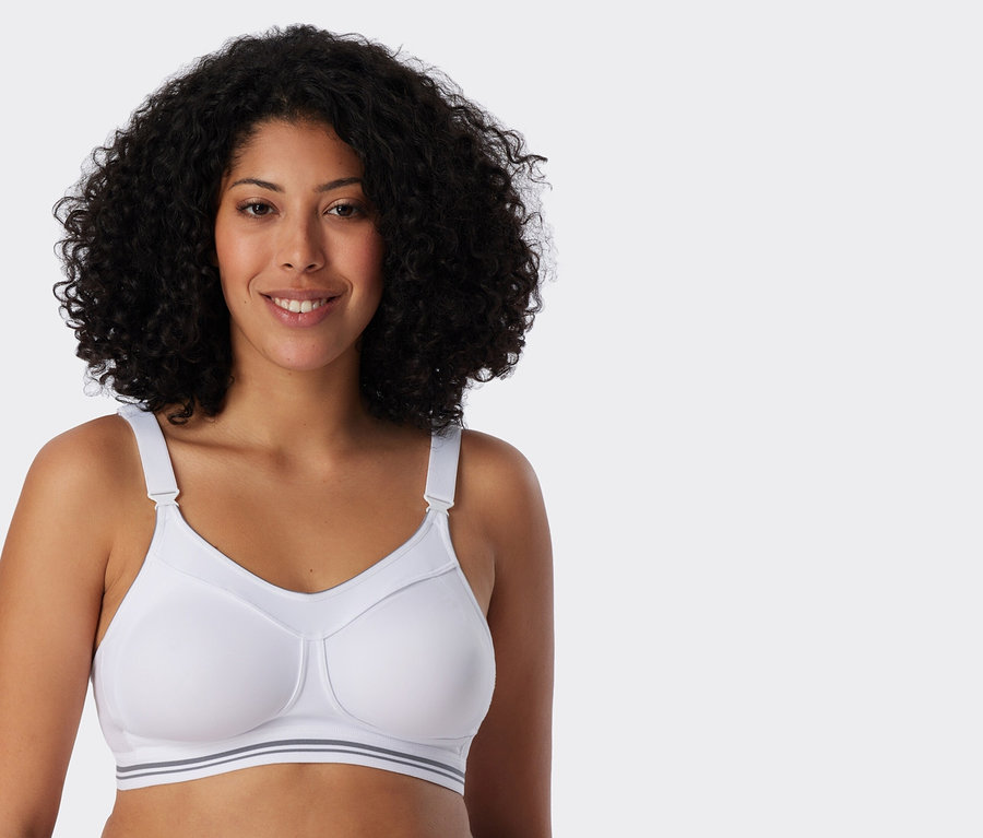 Kobieta z kręconymi włosami ma na sobie biały biustonosz sportowy.