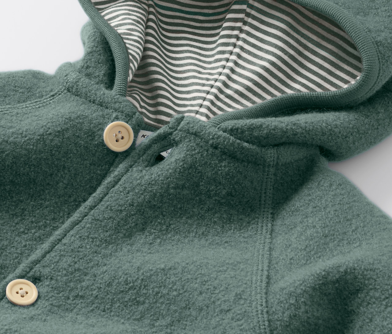 Szczegółowy widok kombinezonu z wełną, zapinanego na guziki i z kapturem w paski.