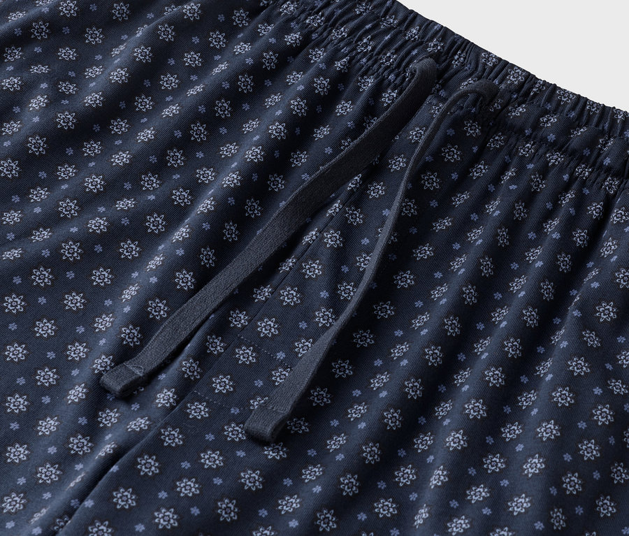Zbliżenie granatowych spodni od piżamy we wzory kwiatowe ze sznurkiem.