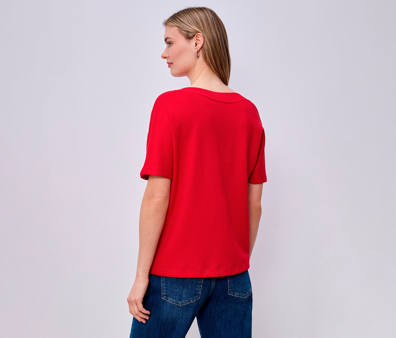 Kobieta od tyłu w czerwonej koszulce Street One i dżinsach.