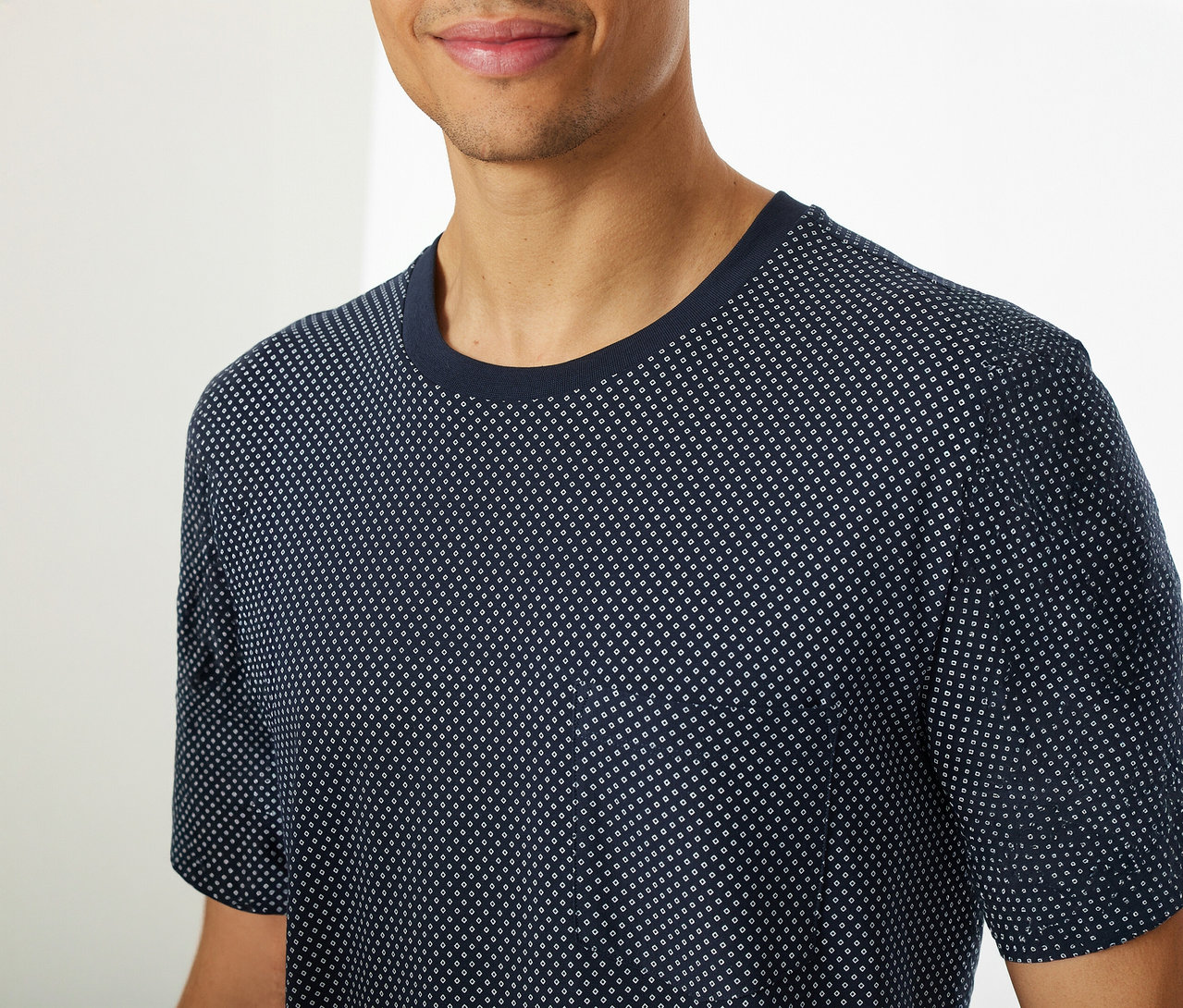 Mężczyzna ma na sobie piżamę z krótkimi spodenkami SCHIESSER, składającą się z niebieskiej koszulki z krótkim rękawem w kropki.