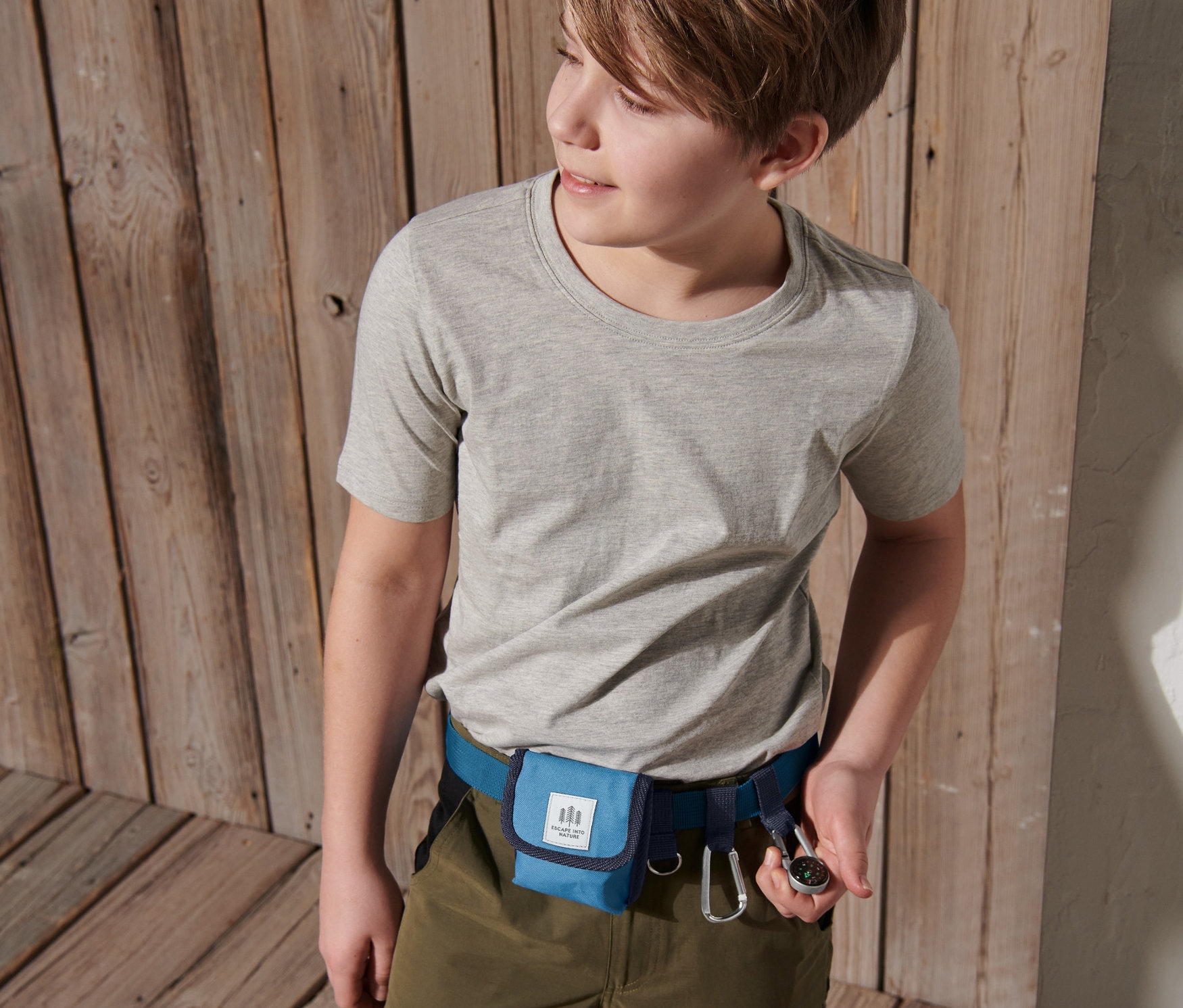 Chłopiec ma na sobie niebieski pas na przybory dla dziecka i trzyma kompas.