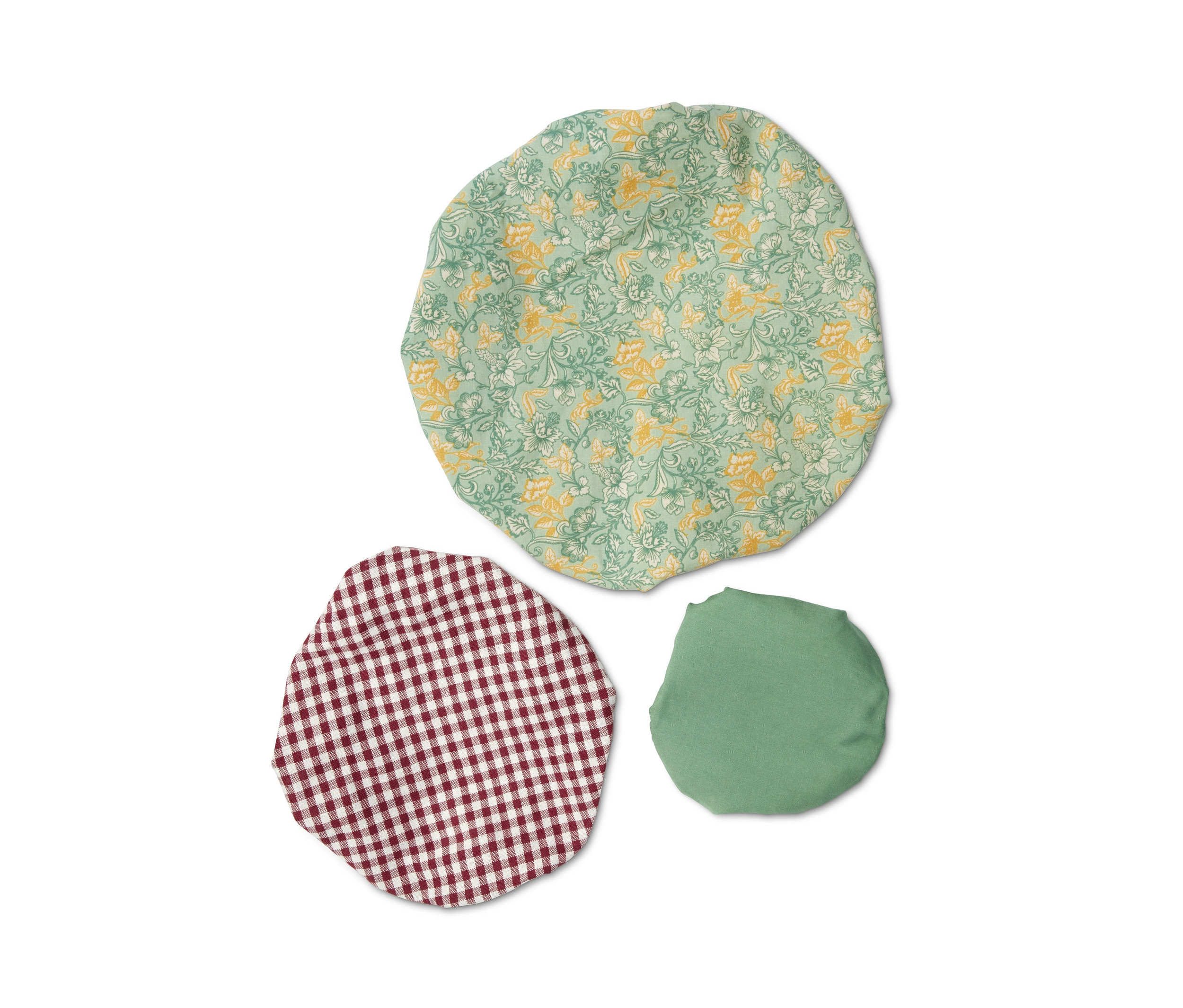 Trzy materiałowe przykrywki na miski z różnymi wzorami leżą na białym tle.