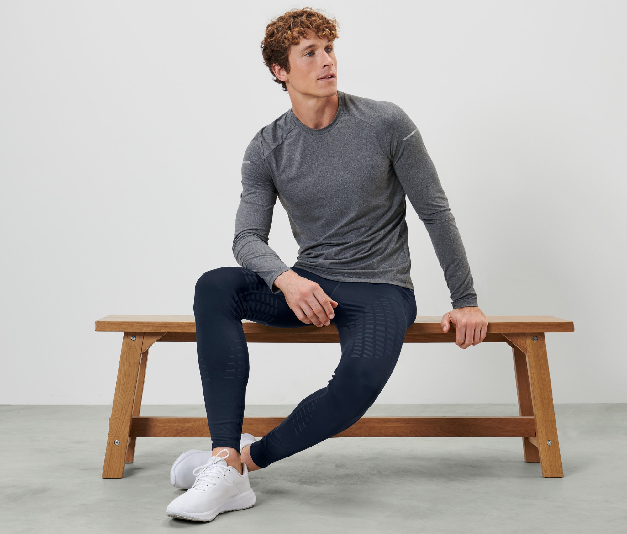 Mężczyzna siedzi na ławce, ubrany w legginsy do biegania.