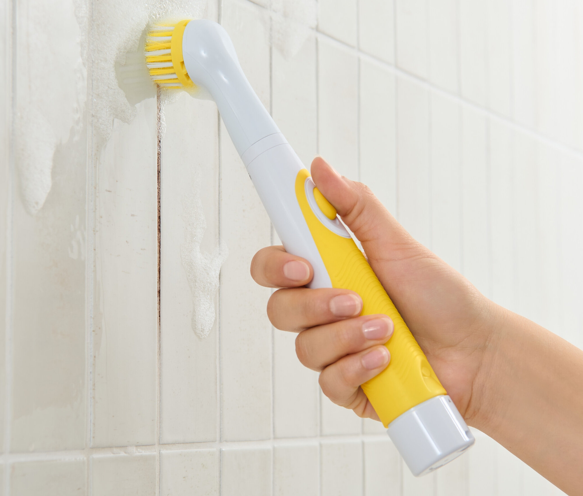 Ręka używa elektrycznej szczotki czyszczącej na brudnych płytkach.