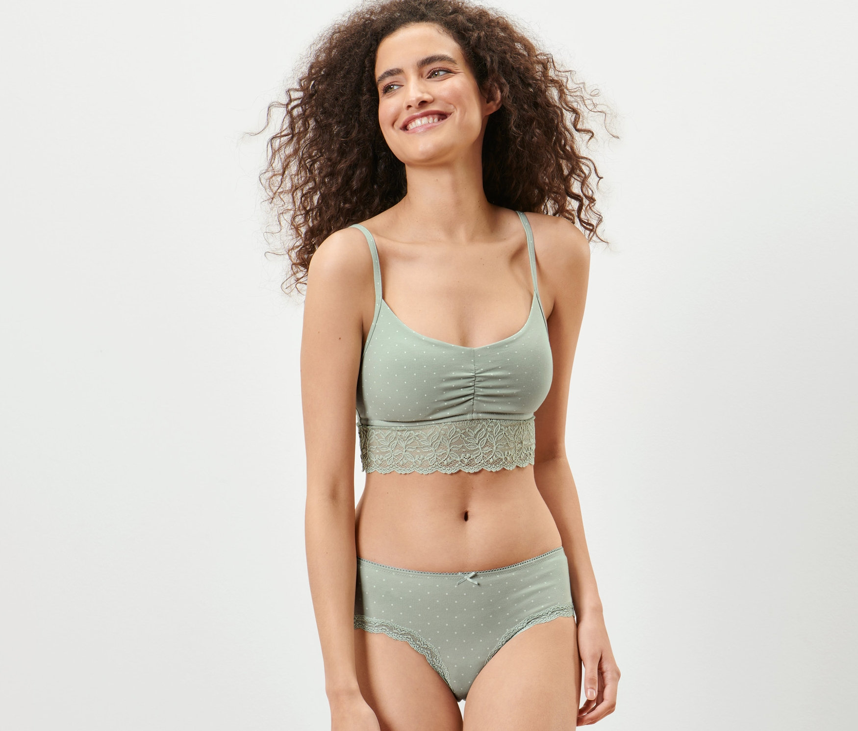 Kobieta ma na sobie jasnozielony biustonosz i figi biodrówki, 2 pary.