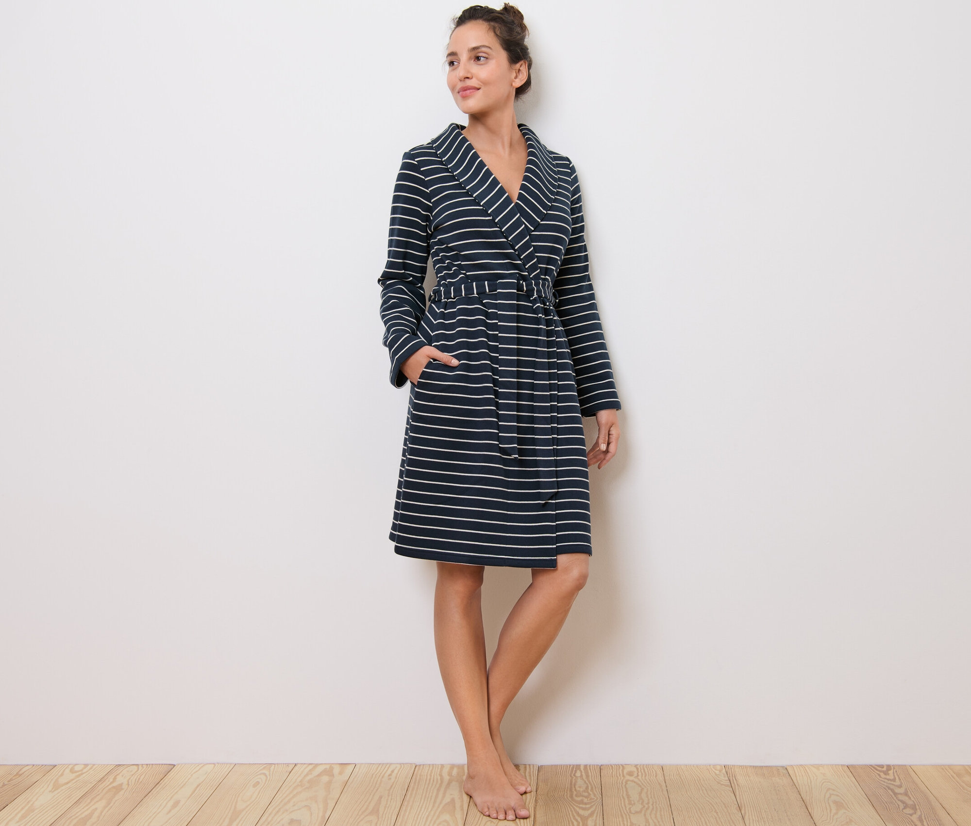 Kobieta stoi i ma na sobie szlafrok w paski.