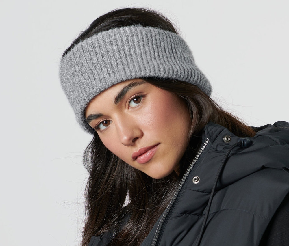 Kobieta ma na sobie opaskę z dzianiny i czarną kamizelkę.