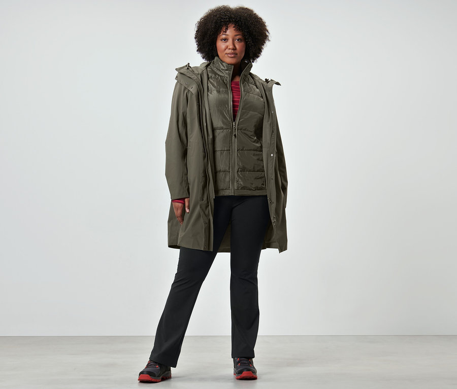 Kobieta ma na sobie płaszcz przeciwdeszczowy 3 w 1 z kamizelką, koszulkę sportową z długim rękawem i spodnie termiczne.