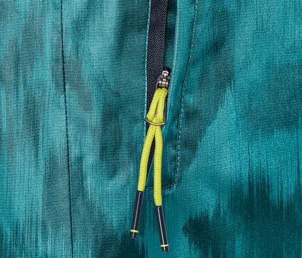 Zbliżenie na spodnie przeciwdeszczowe z nadrukiem i częściowo rozpiętym zamkiem błyskawicznym.