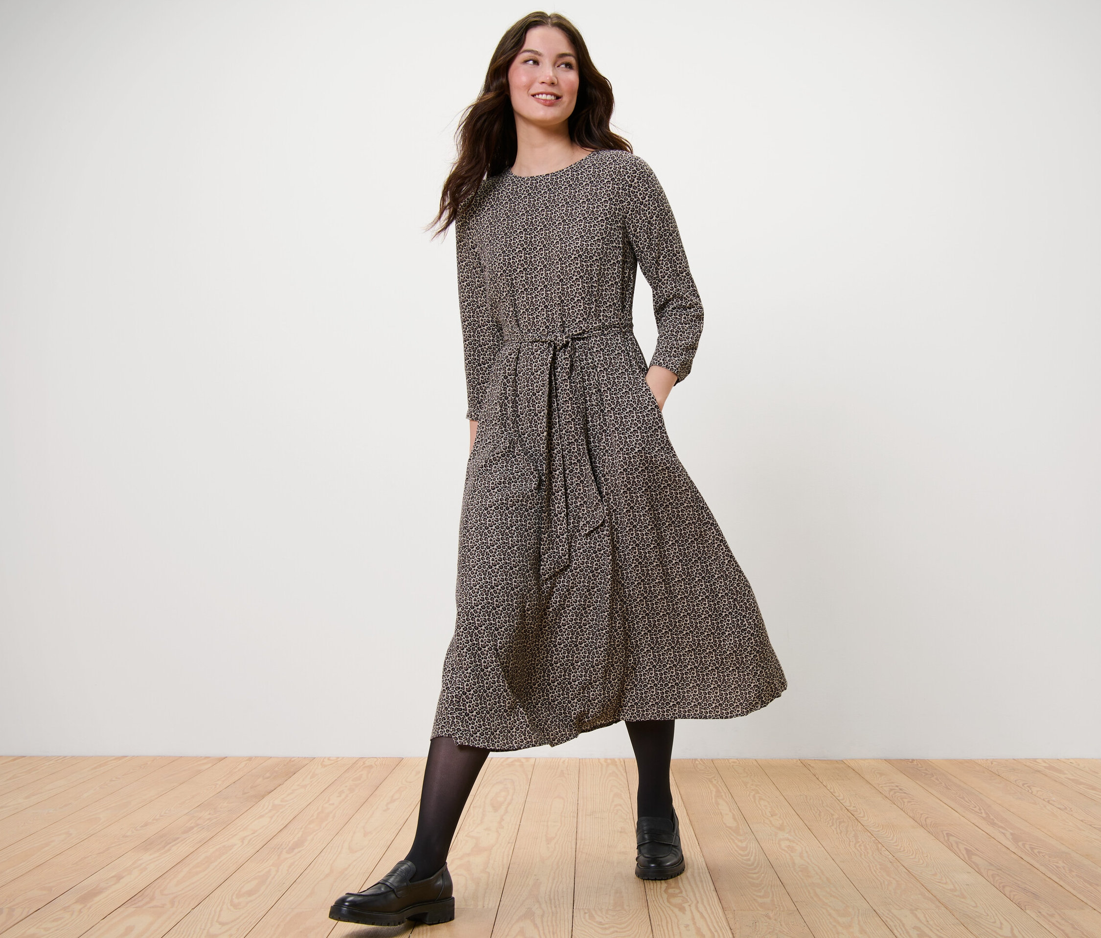 Kobieta idzie i ma na sobie wzorzystą sukienkę z tkaniny.