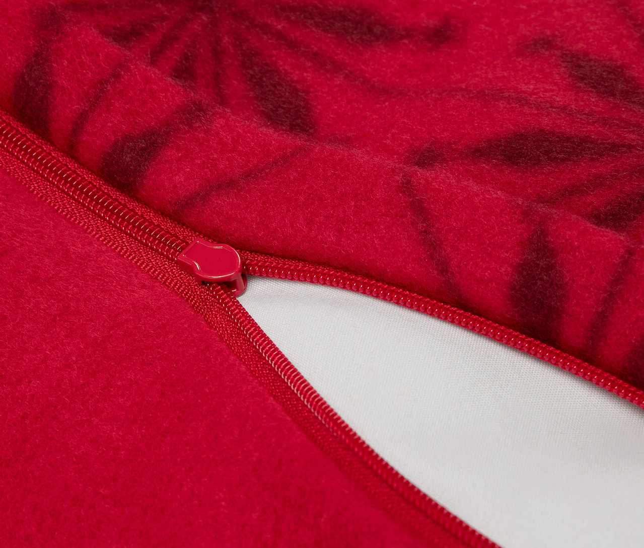 Zbliżenie czerwonej poszewki na poduszkę z zamkiem błyskawicznym i ciemnym kwiatowym wzorem.