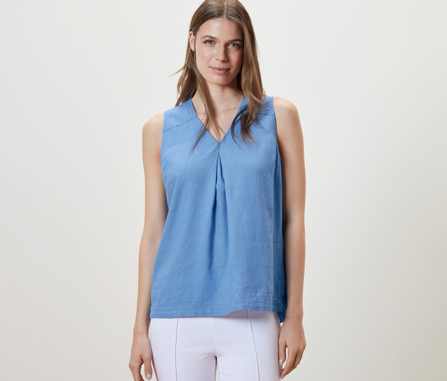 Kobieta ma na sobie jasnoniebieską lnianą bluzkę bez rękawów.