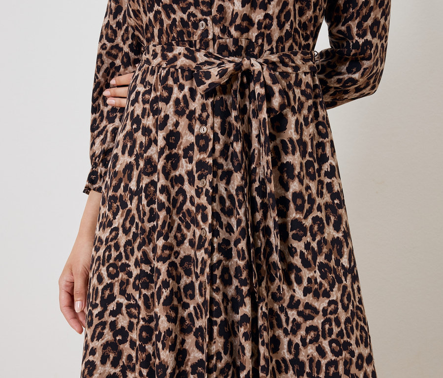 Częściowy widok kobiety w brązowej sukience w zwierzęcy wzór z paskiem.