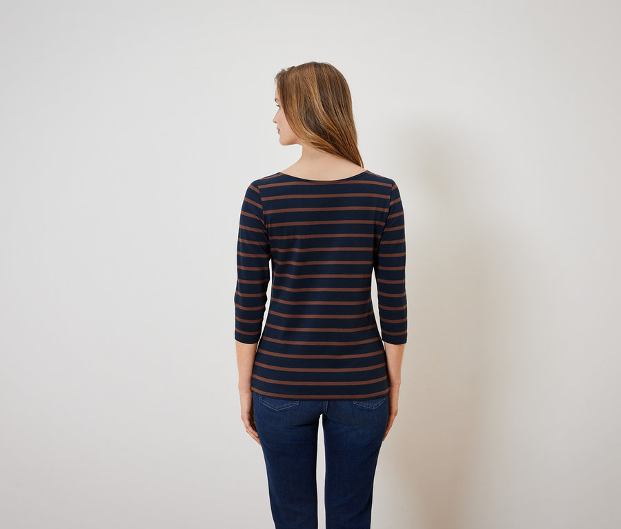 Widok z tyłu kobiety w bluzce w niebiesko-brązowe paski i niebieskich dżinsach.