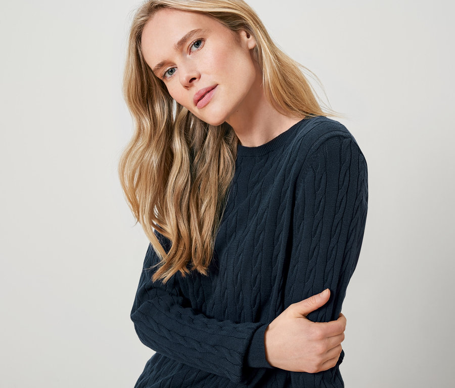 Blondynka ma na sobie granatowy sweter.