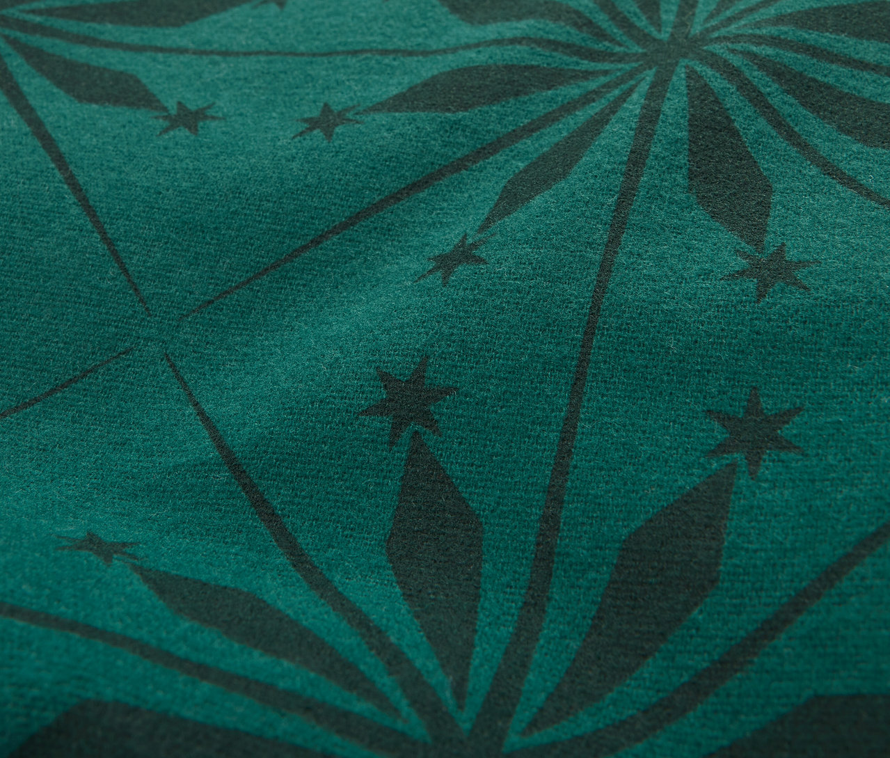 Zbliżenie na ciemnozieloną tkaninę z czarnym wzorem gwiazd.