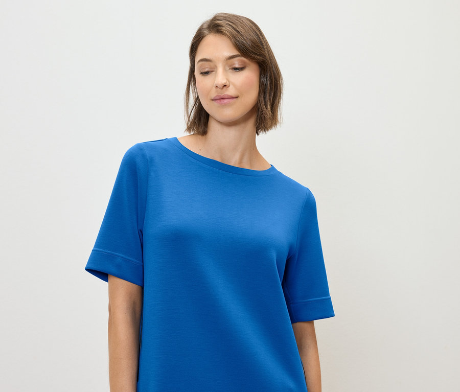 Kobieta ma na sobie niebieską koszulkę.