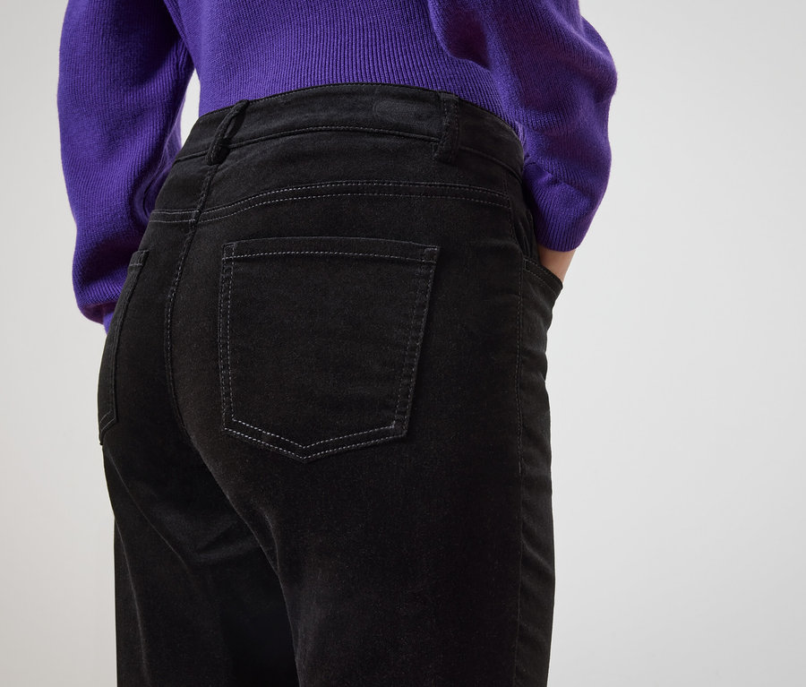 Widok z tyłu kobiety w czarnych dżinsach i fioletowym swetrze.