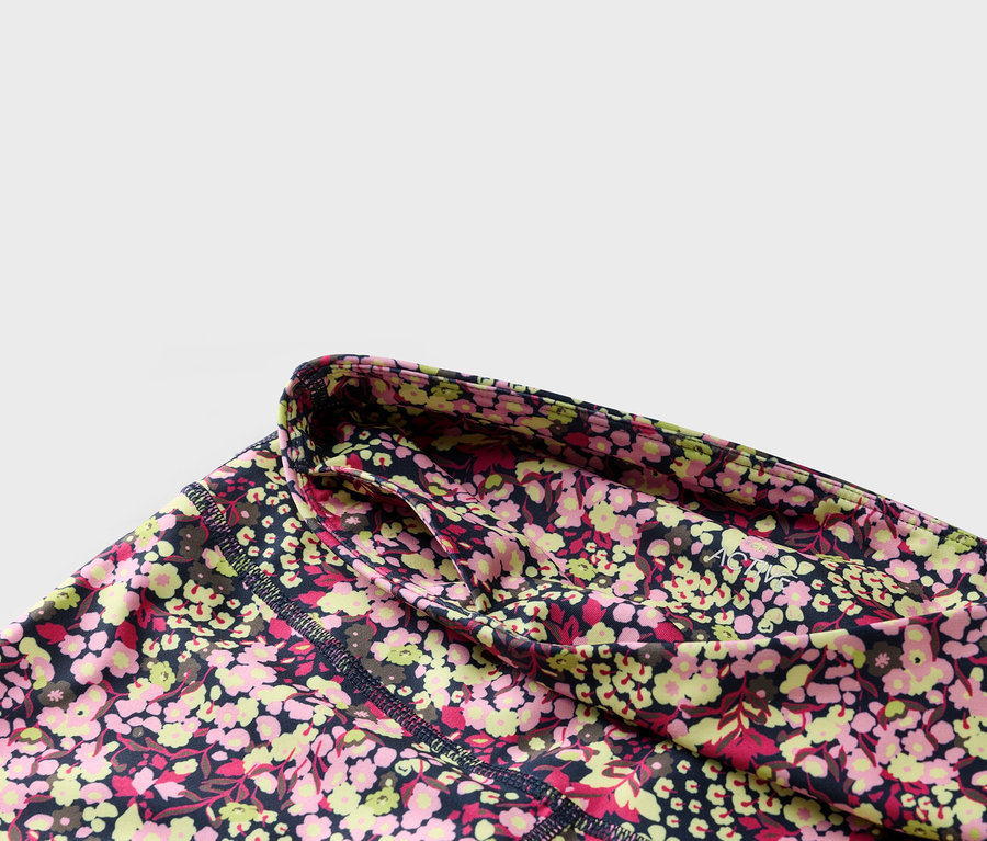 Zbliżenie kwiecistych legginsów z granatowym pasem i boczną kieszenią.