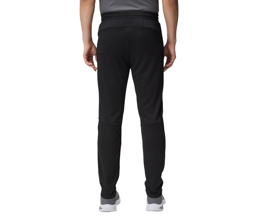 Zbliżenie na tył osoby ubranej w czarne spodnie dresowe i szare buty.