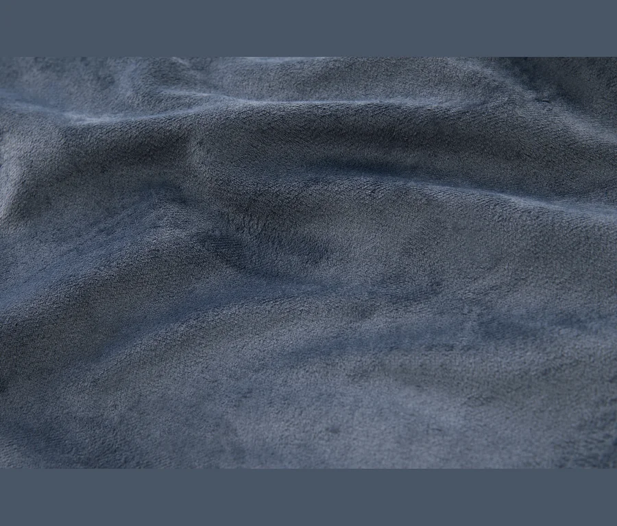 Zbliżenie miękkiego, teksturowanego niebieskiego materiału z widocznymi fałdami i zagnieceniami.