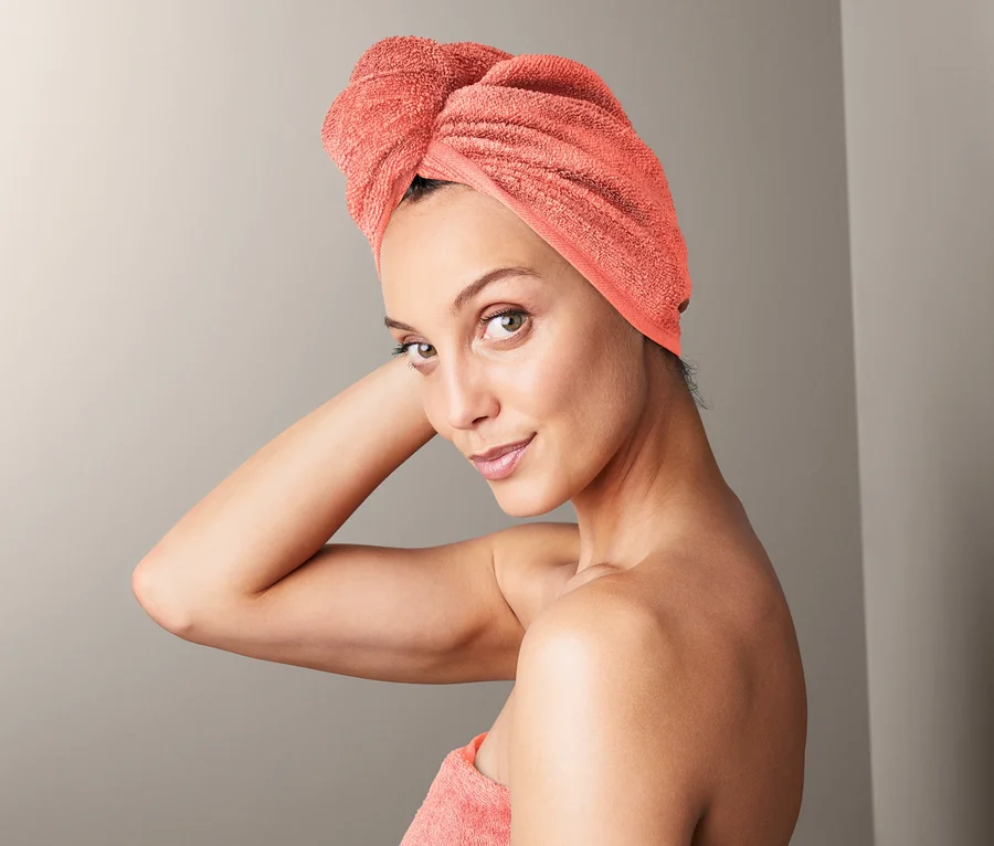 Kobieta z ręcznikiem z turbanem na głowie i ręcznikiem owiniętym wokół ciała.
