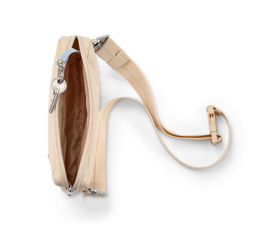 Otwarta, beżowa torba na ramię z zabezpieczonym paskiem i kluczami w środku.