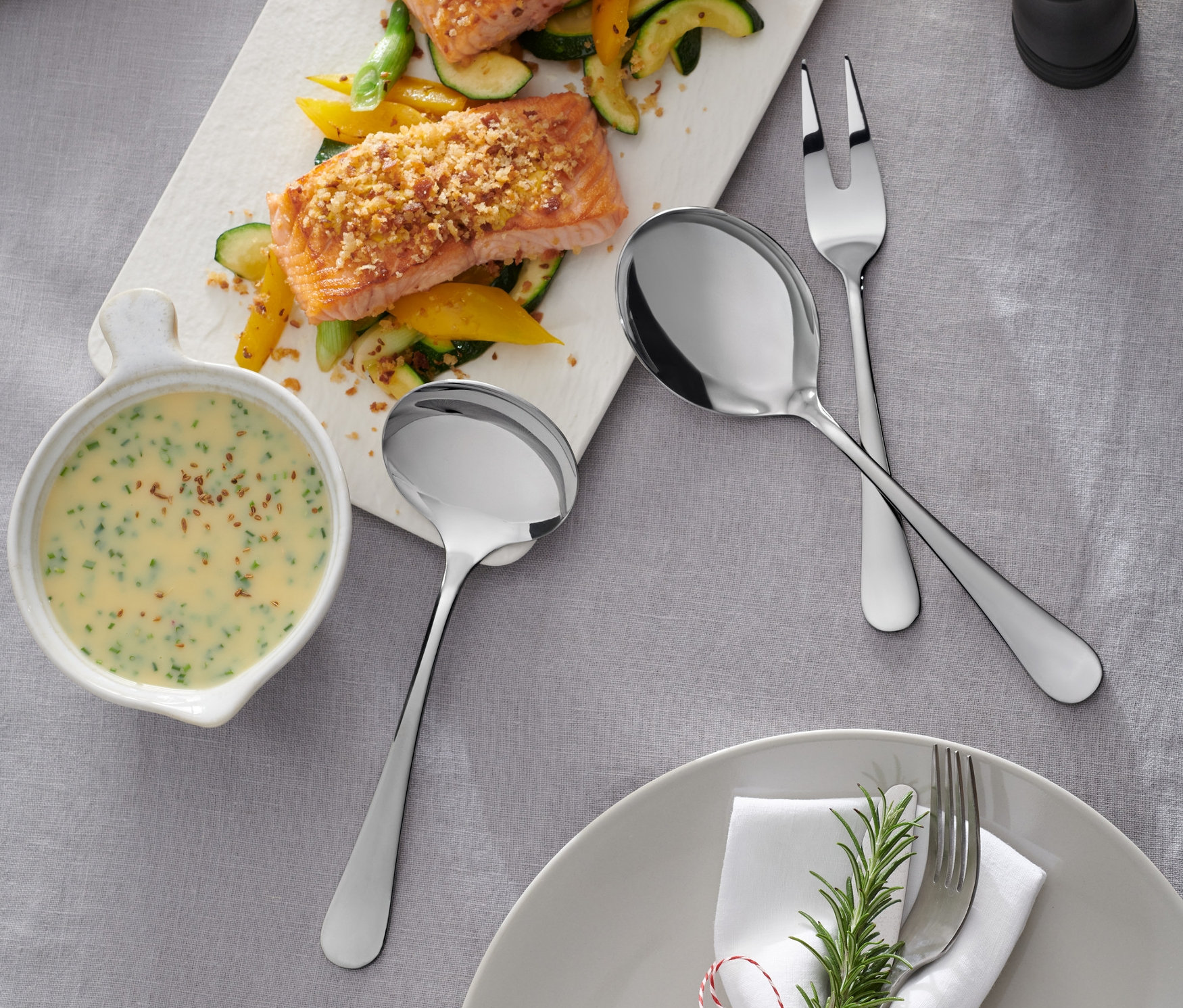 Łosoś, cukinia i żółta papryka na tacy ze sztućcami do nakładania.