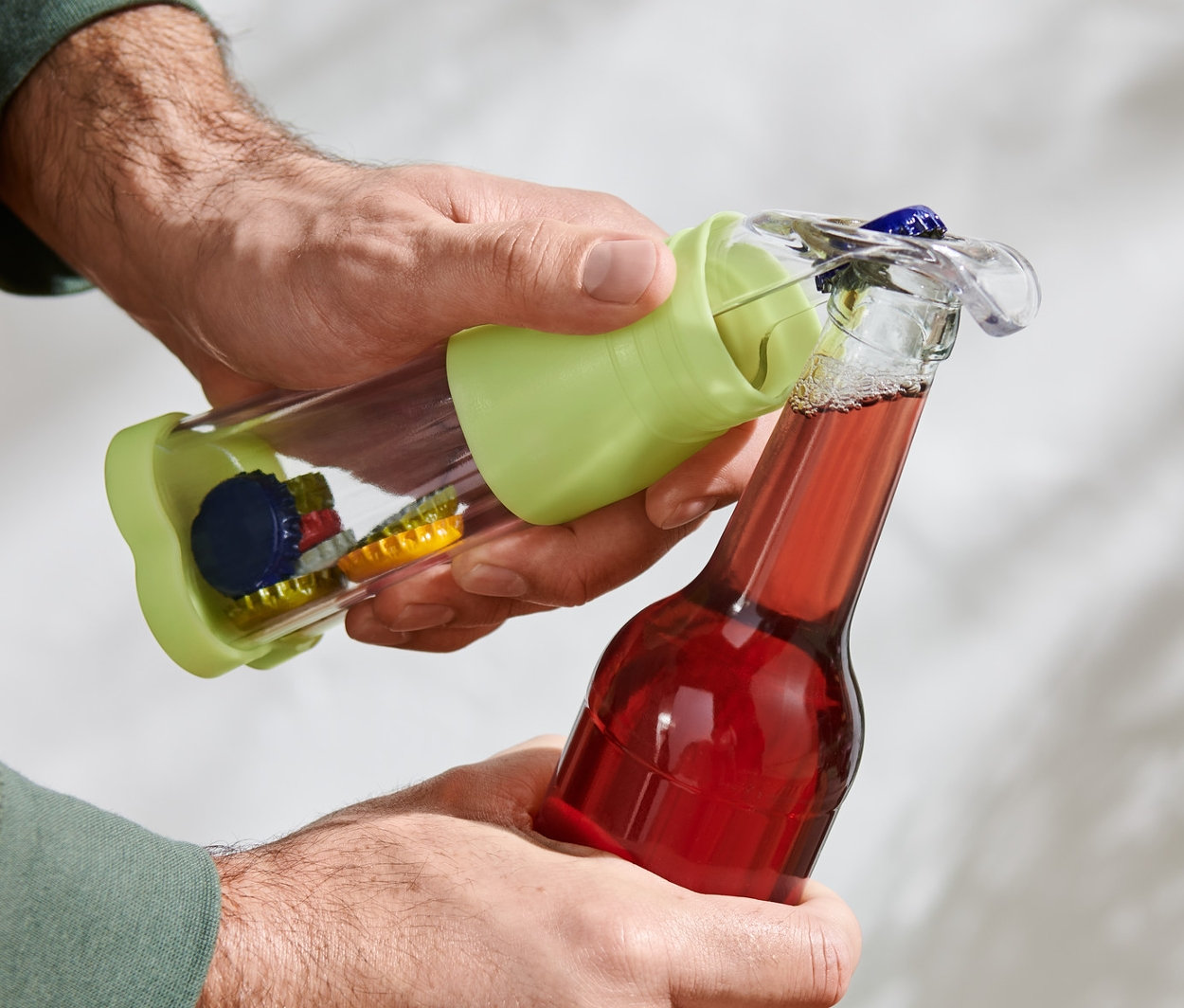 Mężczyzna otwiera czerwoną butelkę otwieraczem do butelek z pojemnikiem.