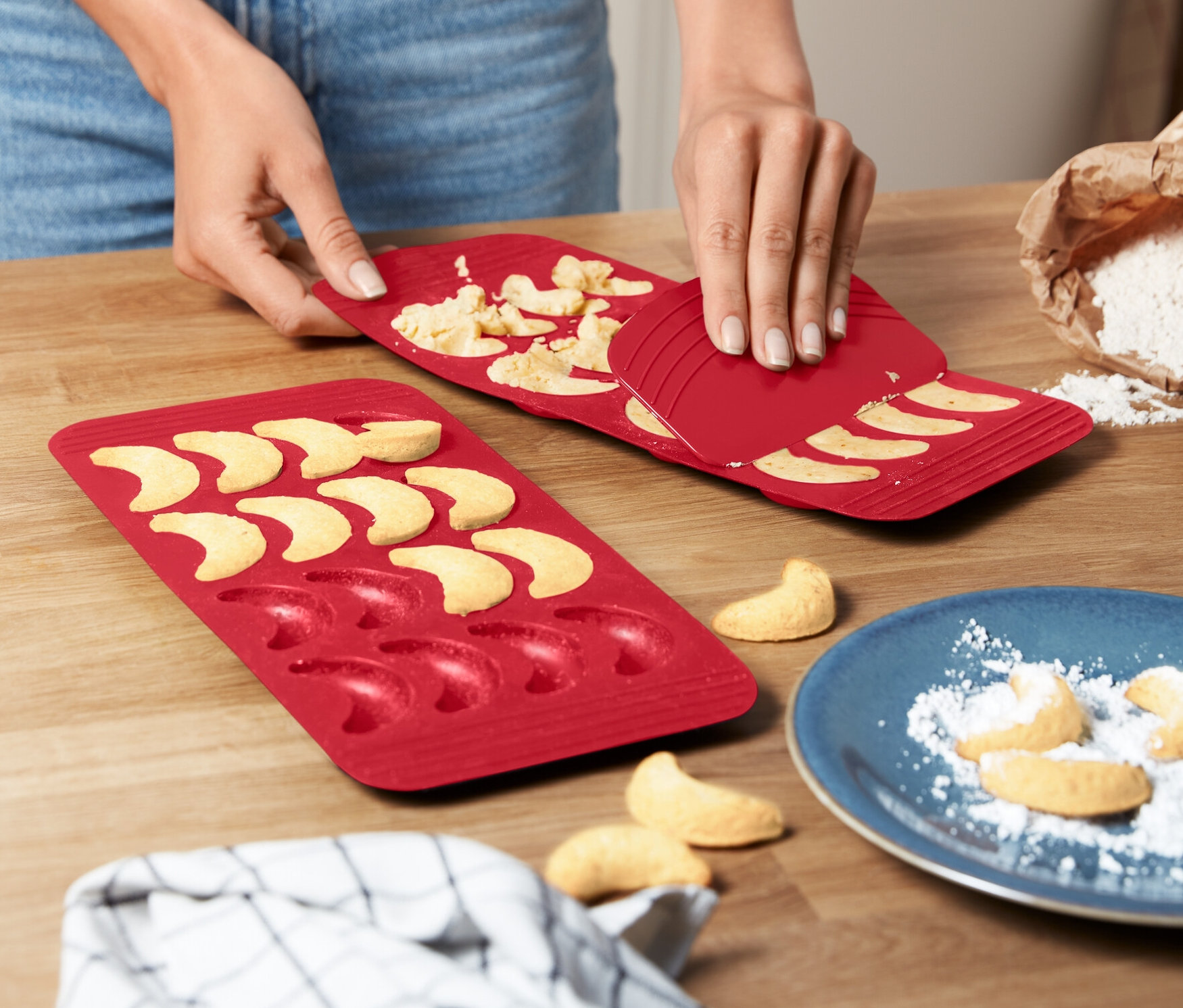 Kobieta wyjmuje rogaliki z czerwonej maty do pieczenia ciastek-rogalików (2 sztuki).