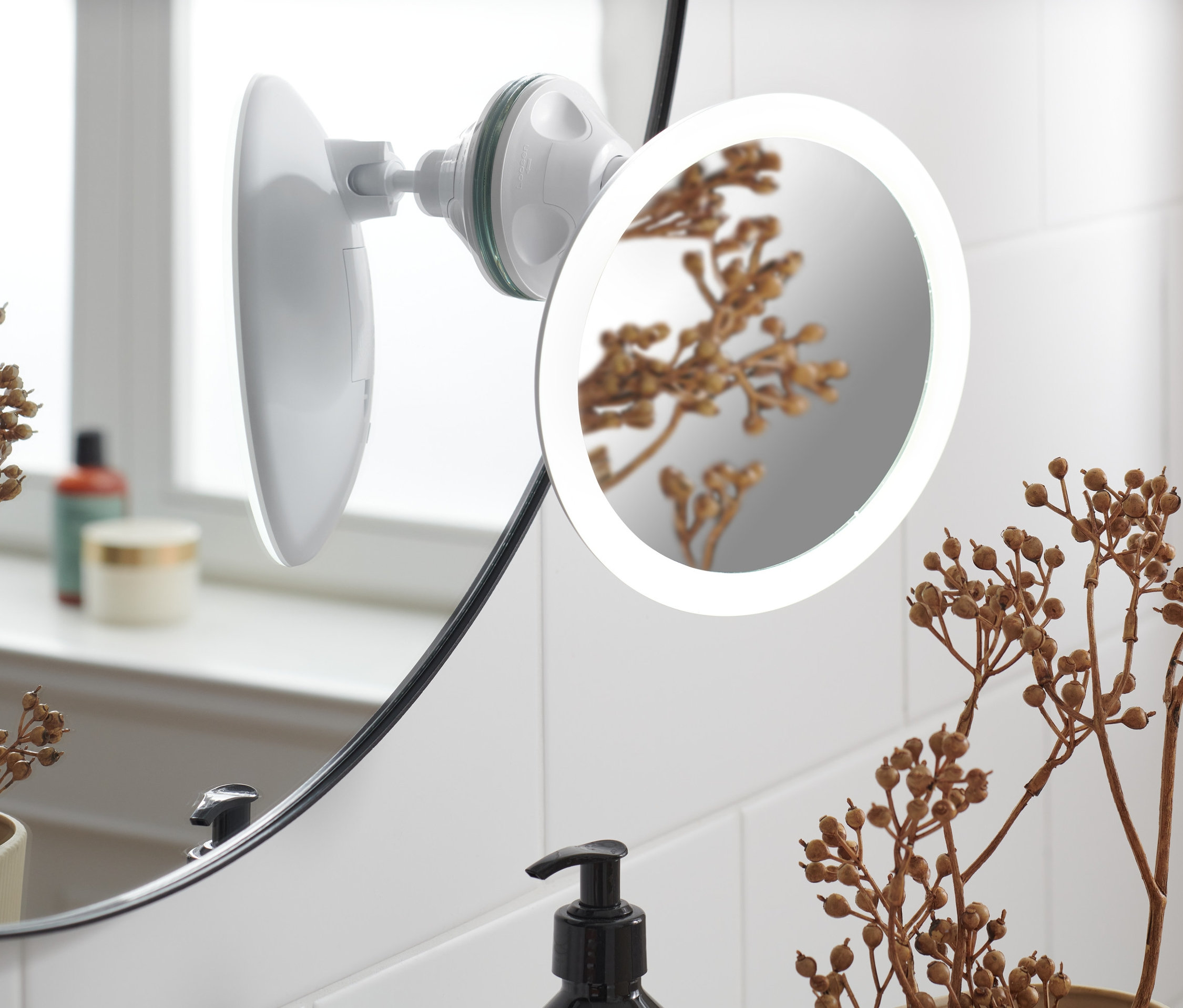 Zbliżenie na lusterko kosmetyczne z podświetleniem LED przymocowane do ściany z płytek.