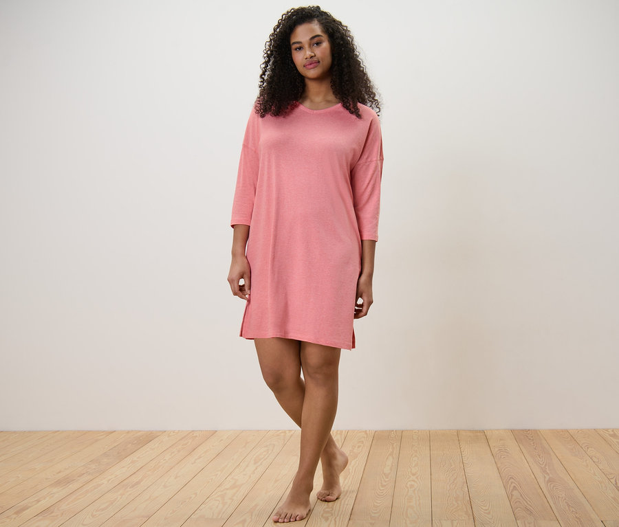 Kobieta stoi boso w koszuli nocnej.