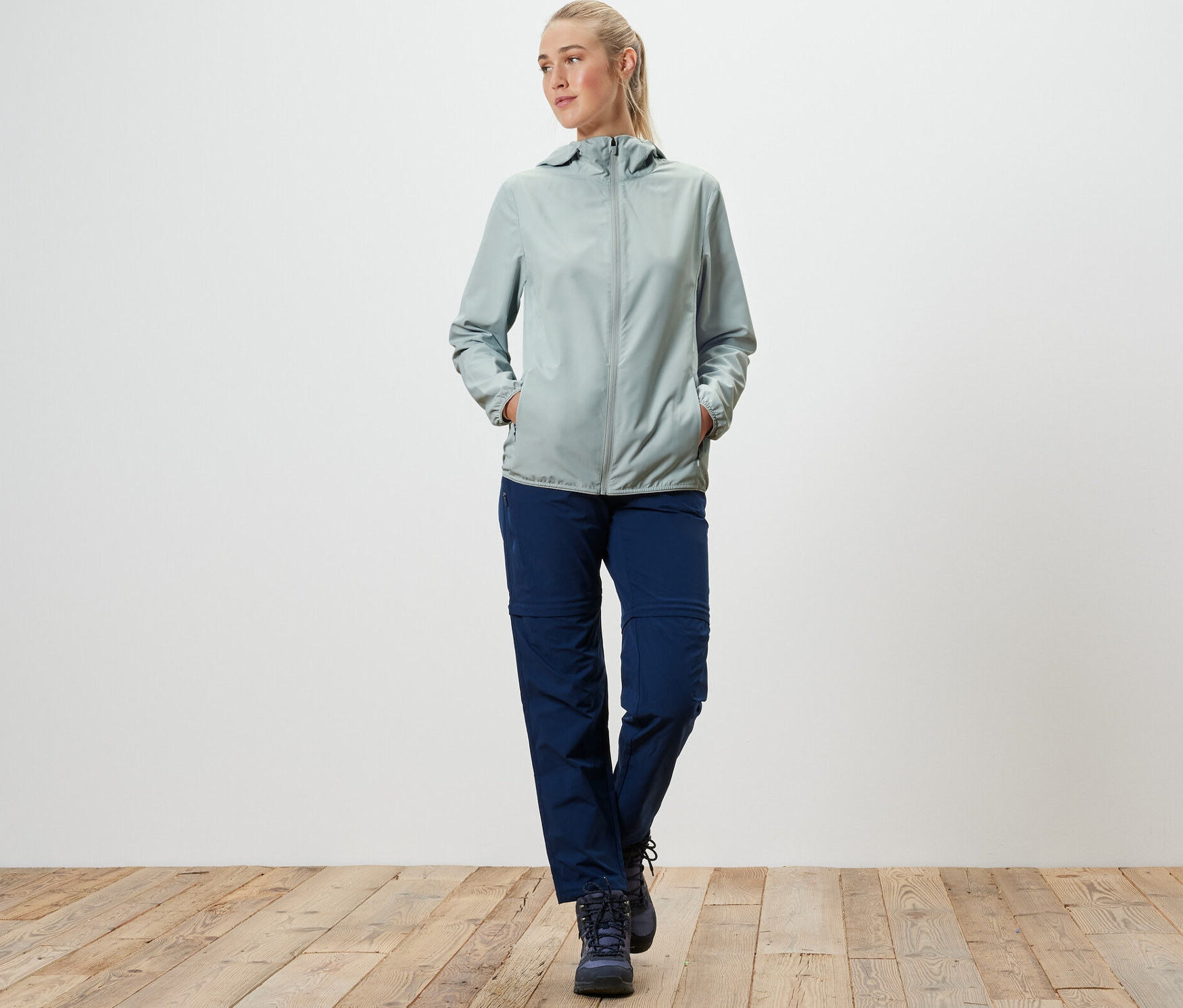 Kobieta idzie i ma na sobie szarą kurtkę funkcyjną z możliwością spakowania.