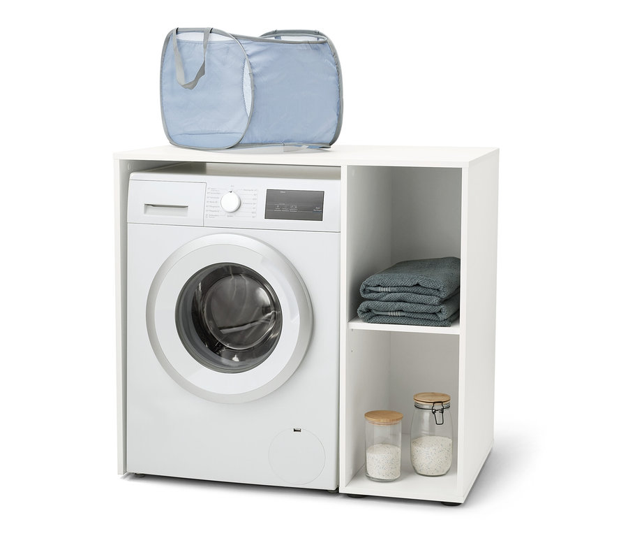 Pralka umieszczona jest w białej szafce na pralkę z bocznym schowkiem. Na pralce leży niebieski kosz na pranie.