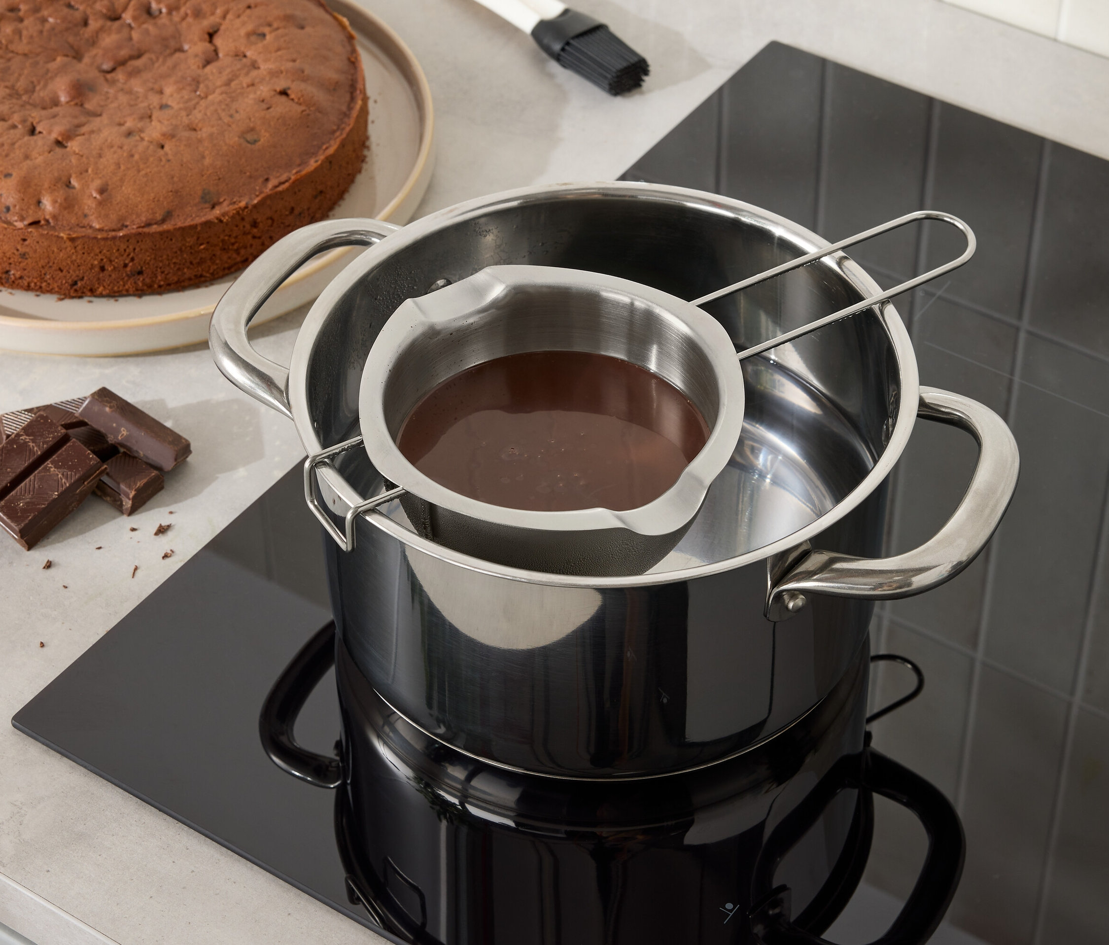 Ciasto czekoladowe i czekolada roztapiają się w misce ze stali nierdzewnej nad garnkiem z wodą.