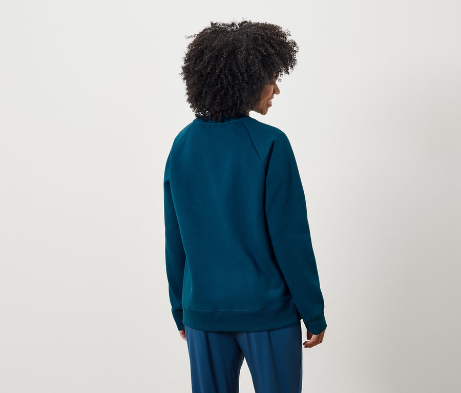 Widok z tyłu kobiety z kręconymi włosami w niebieskiej bluzie i spodniach.