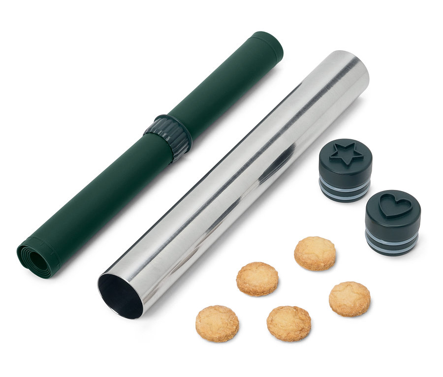 Zielona mata do wałkowania i srebrny wałek z foremkami do ciastek w kształcie gwiazdy i serca oraz ciasteczka.