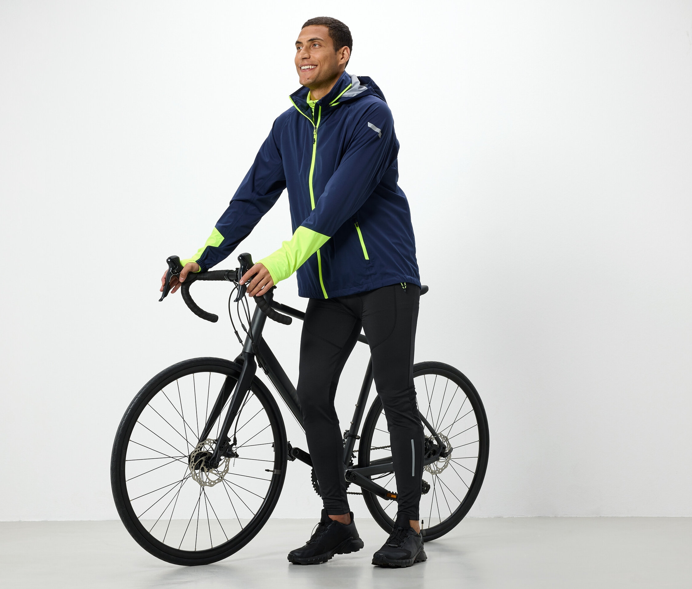 Mężczyzna w kurtce trzyma czarny rower.