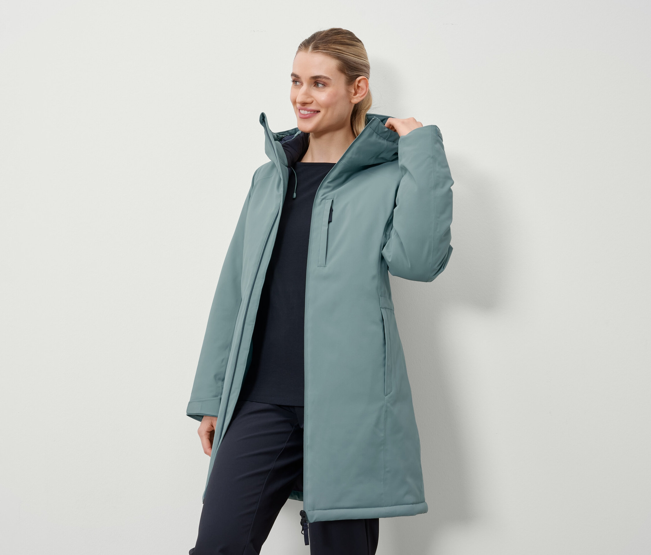 Kobieta ma na sobie długi płaszcz w kolorze benzyny.