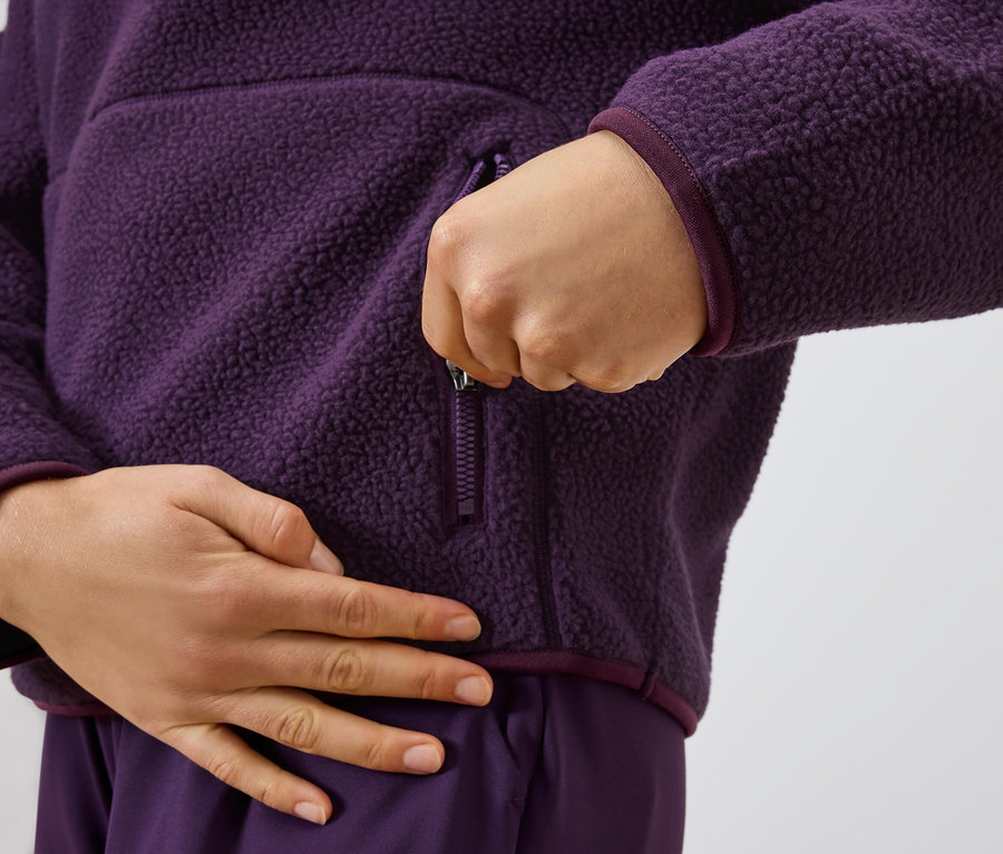Osoba zapina zamek błyskawiczny w fioletowej bluzie polarowej.