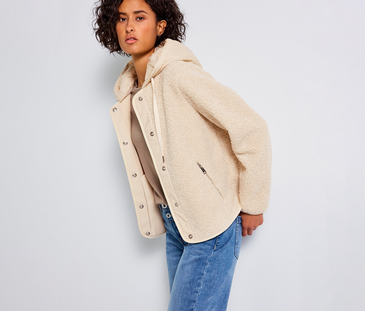 Kobieta ma na sobie pluszową bluzę z odpinanym kapturem Street One i dżinsy.