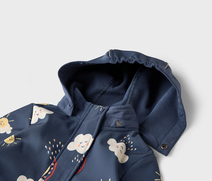 Zbliżenie na granatową kurtkę z kapturem, ozdobioną motywami chmur i słońca.