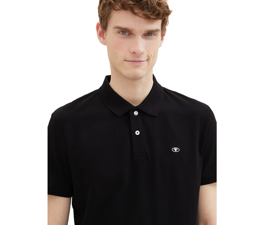 Mężczyzna ma na sobie czarną koszulkę polo Tom Tailor z dzianiny pique.
