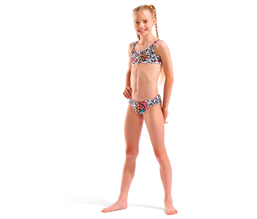 Uśmiechnięta dziewczyna z blond warkoczami ubrana w białe bikini z kolorowym wzorem.